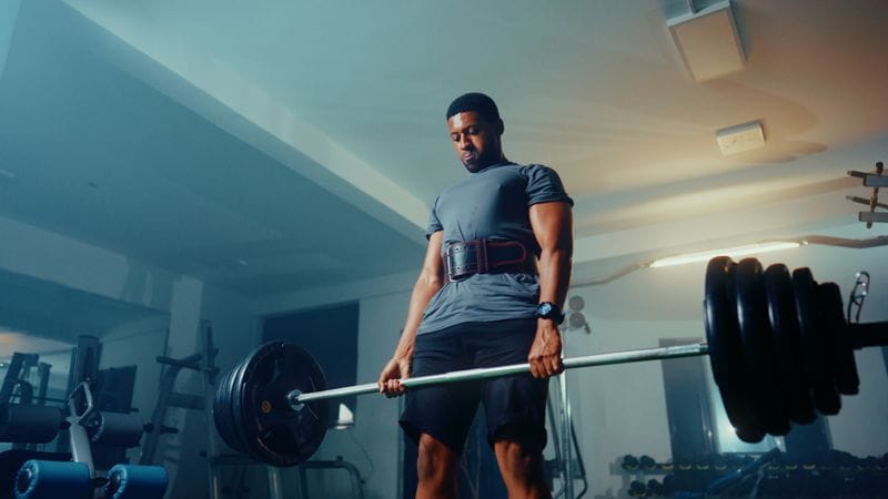 Strong athlete performing deadlift with barbell technique fixes for beginners in modern gym setting showing neutral spine and hip hinge position